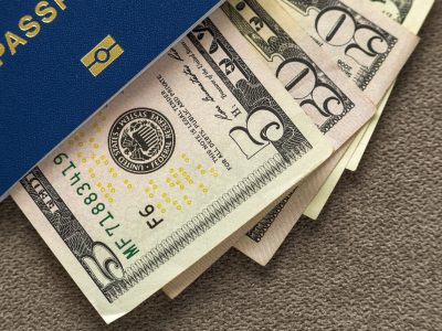 Travel passport and money, American dollars banknotes bills on copy space background, top view. Traveling and finance problems concept.